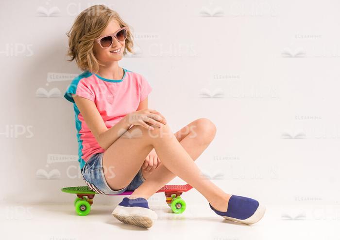 Young Girl Sitting On Skateboard Stock Photo