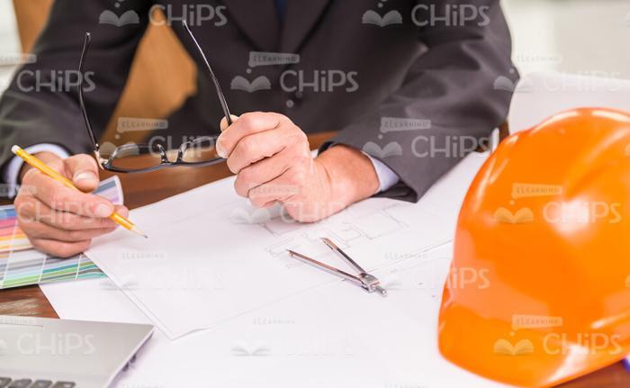 Male Architect Holding Glasses And Working On Drawing Stock Photo