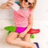 Smiling Little Girl With Skateboard Sitting On Floor While Taking Selfie Stock Photo