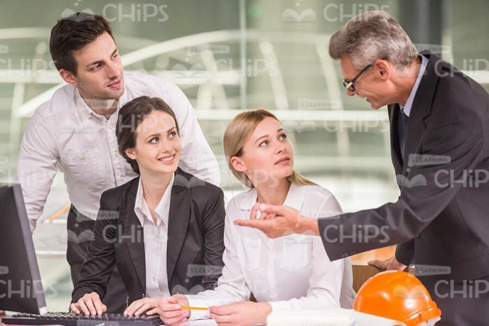 Lead Engineer Explaining Something To Young Colleagues Stock Photo
