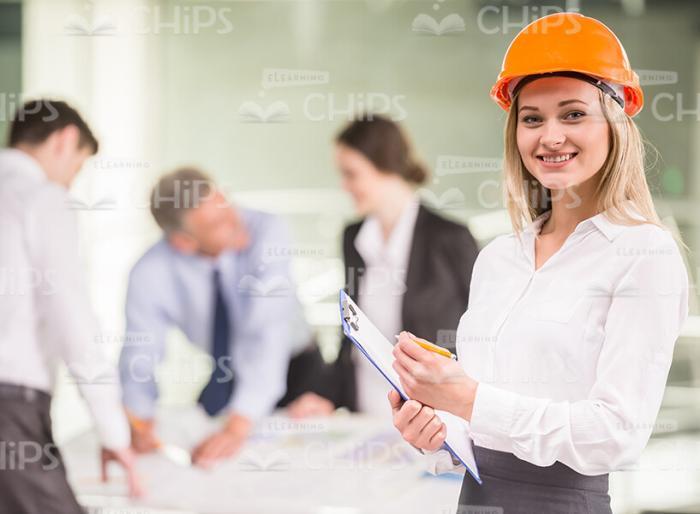 Smiling Woman Wearing Hard Hat And Holding Clipboard Stock Photo