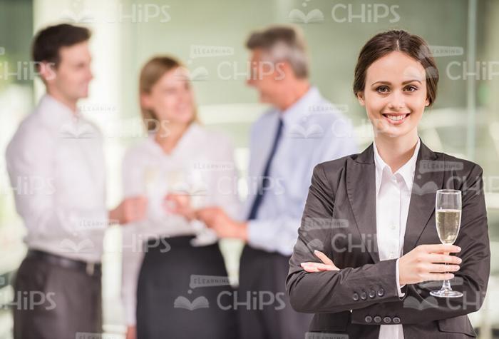Smiling Businesswoman With Glass In Front Of Her Colleagues Stock Photo