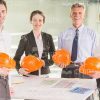 Architects Holding Orange Hard Hats Stock Photo