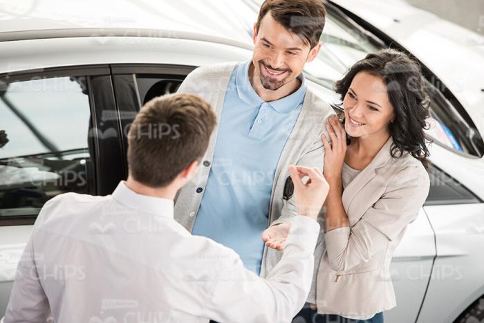 Car Seller Explains Something To Couple Stock Photo