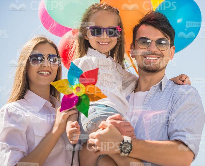 Smiling Young Family With Plastic Flower And Balloons Stock Photo