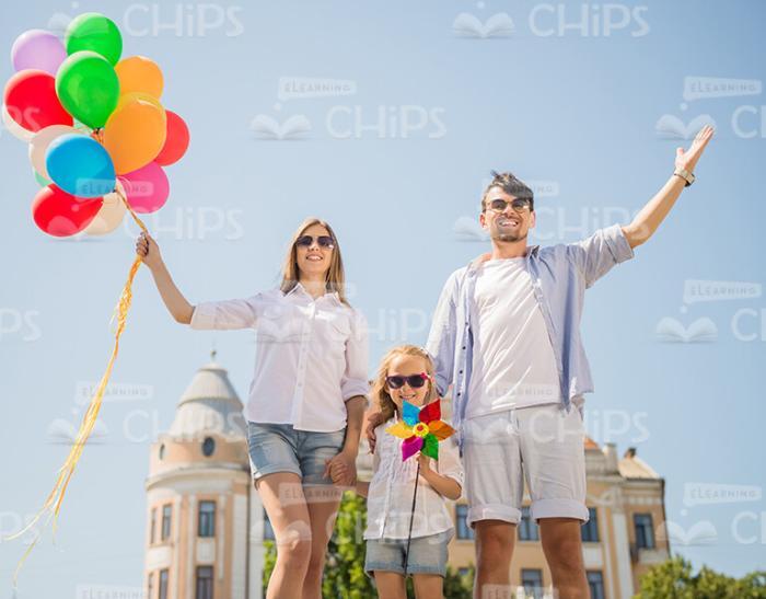 Smiling Family Walking With Bunch Of Balloons Stock Photo