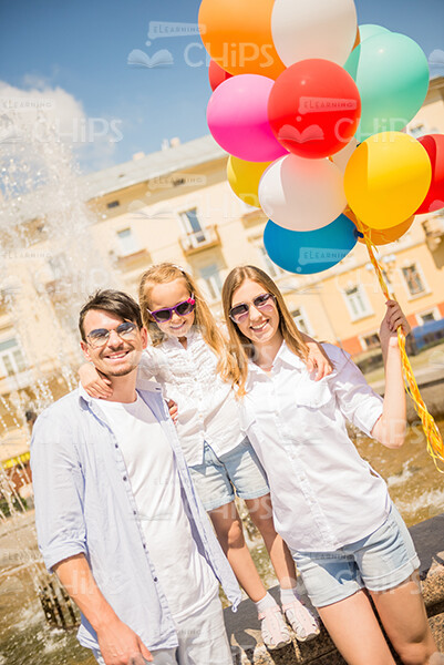 Happy Young Family With Balloons Walking Through The City Stock Photo