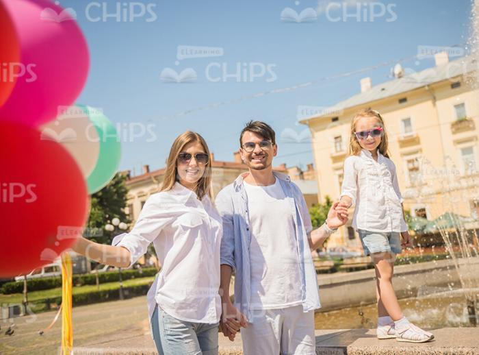 Smiling Family Walking Outdoor With Bunch Of Balloons Stock Photo