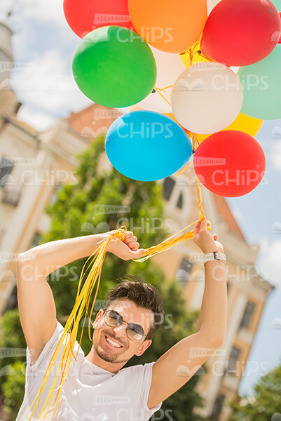 Smiling Young Man Holding Balloons With His Raised Hands Stock Photo Smiling Young Man Holding Balloons With His Raised Hands Stock Photo