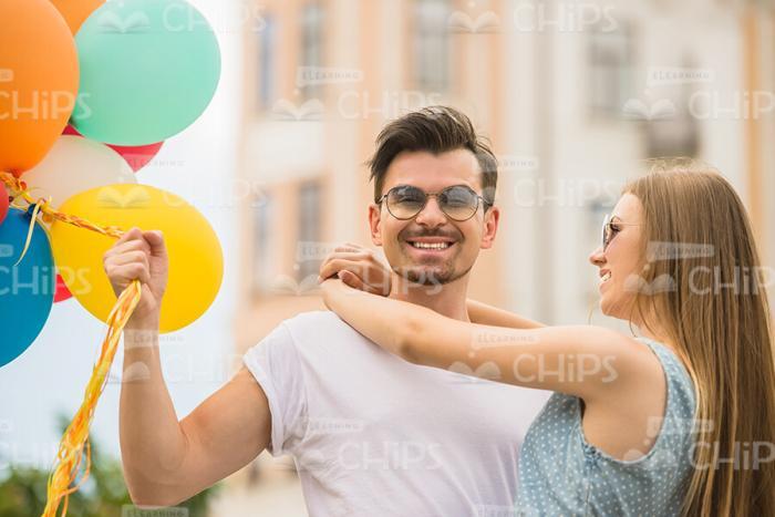Young Woman Hugging Happy Man Who Is Holding A Bunch Of Balloons Stock Photo