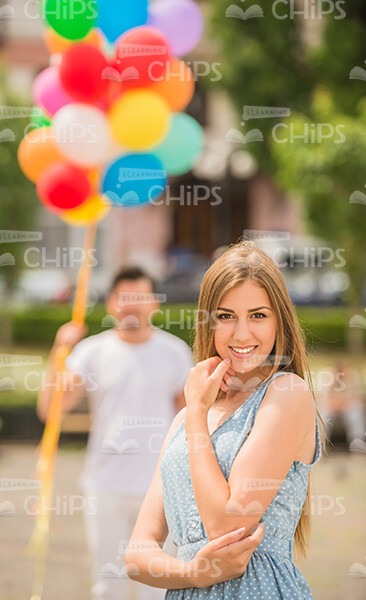 Cute Young Woman And Her Boyfriend With Bunch Of Balloons On Background Stock Photo