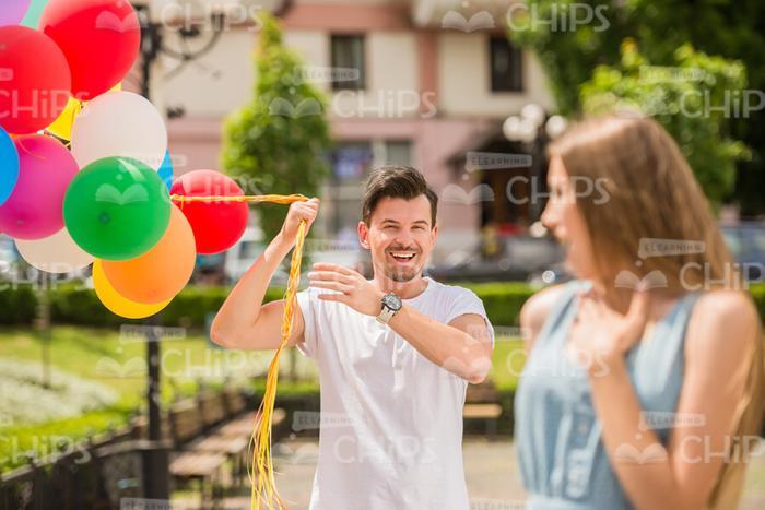 Young Man With Stack Of Balloons Meeting Her Girlfriend Stock Photo