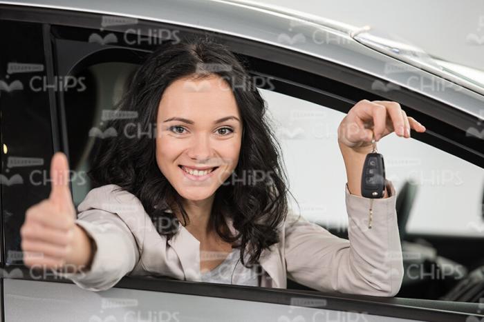 Handsome Woman Sitting In Car, Holding Keys And Showing Her Thumb Up Stock Photo