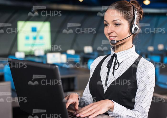 Businesslady With Headset Typing On Laptop Stock Photo
