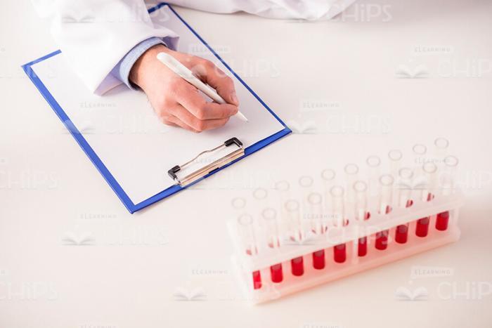 Researcher's Hand Writing On Clipboard Stock Photo