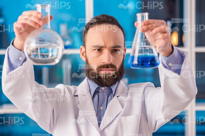 Bearded Researcher Holding Flasks Stock Photo