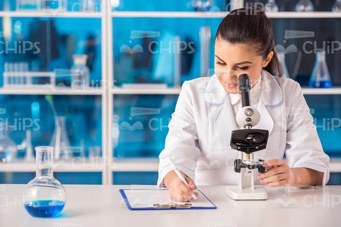 Young Woman Looking Through Microscope Stock Photo