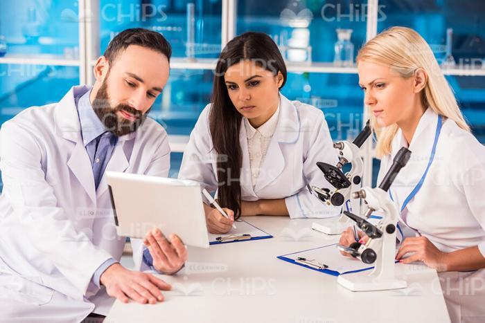 Male Scientist Showing Tablet To Female Researchers Stock Photo