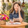 Female Gardener With Mobile Phone Making Notes Stock Photo