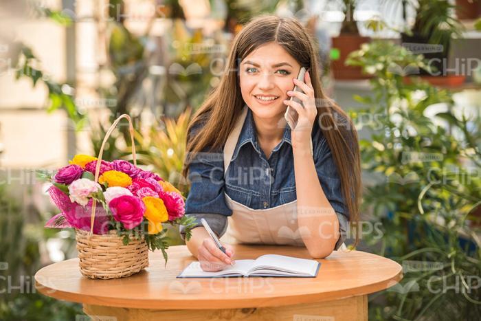 Female Gardener With Mobile Phone Making Notes Stock Photo
