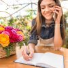 Woman Talks On Phone And Writing In Notebook Stock Photo