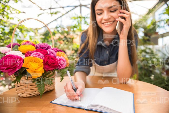 Woman Talks On Phone And Writing In Notebook Stock Photo