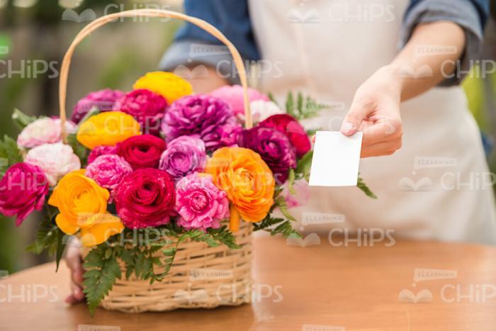Woman's Hand Putting Card Into Basket Of Flowers Stock Photo