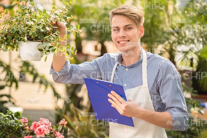 Smiling Man With Clipboard Holding Plant Stock Photo