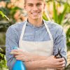 Smiling Young Gardener Crosses Arms And Holds Pulverizer With Scissors Stock Photo