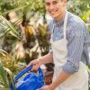Smiling Man Watering Plants In Garden Stock Photo