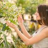 Young Woman Looking On Plant In The Garden Stock Photo