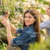 Smiling Female Gardener Touches Plant Stock Photo