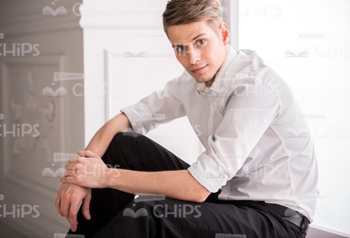 Half-Turned Young Man Sitting On Windowsill Stock Photo