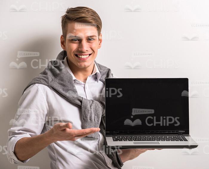 Stock Photo Of Young Man Holding Laptop And Presenting It Stock Photo