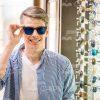 Young Man Wearing New Glasses At Shop Stock Photo