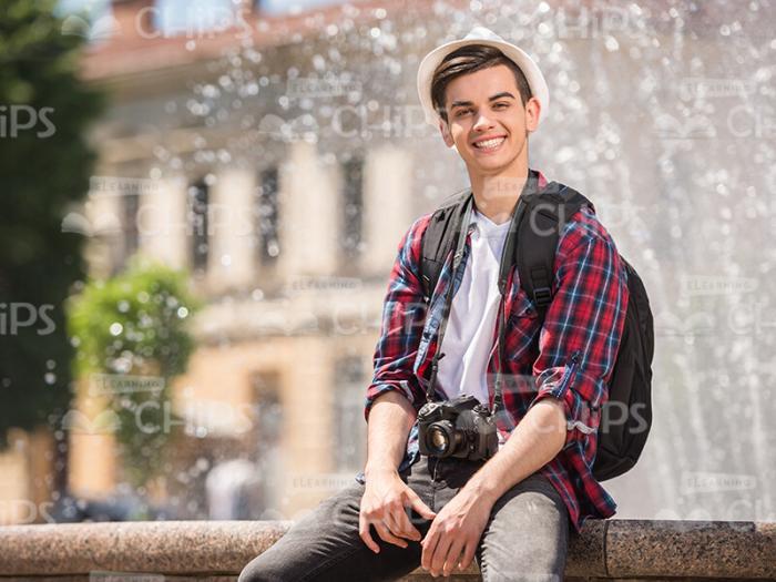 Young Man Sitting In Front Of Fountain Stock Photo
