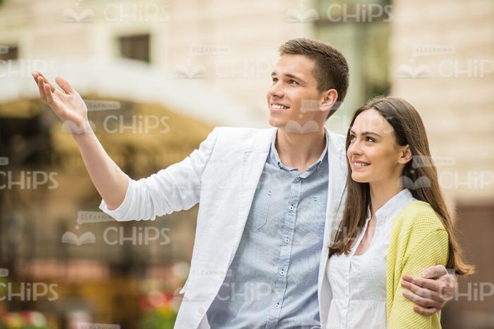 Young Man Pointing Forward While Something To Girlfriend Stock Photo
