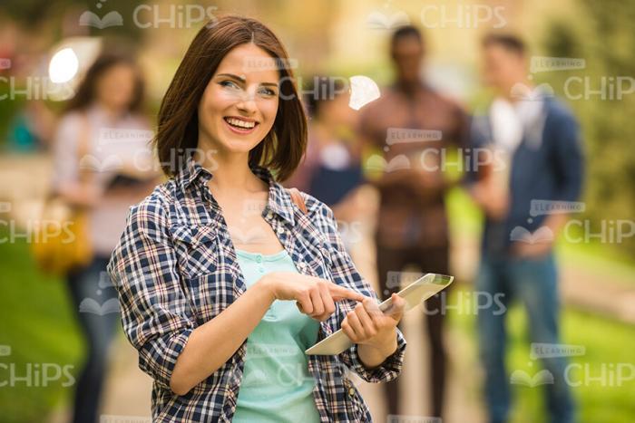 Nice Young Woman Uses Tablet Outdoors Stock Photo