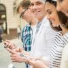 Smiling Man Looks At Camera While Friends Type Messages Stock Photo