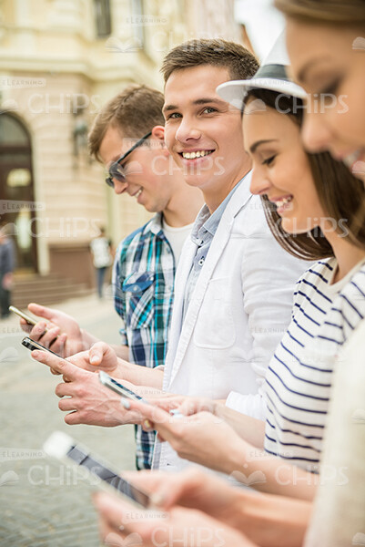 Smiling Man Looks At Camera While Friends Type Messages Stock Photo