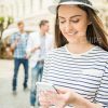 Young Woman Wearing Hat And Typing Message On Her Phone Stock Photo