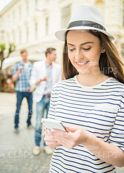 Young Woman Wearing Hat And Typing Message On Her Phone Stock Photo
