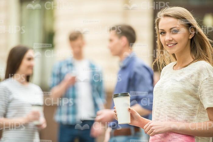 Nice Girl Standing Half-Turned And Holding Coffee Cup Stock Photo