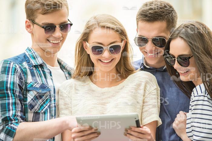 Young Woman Using Tablet While Her Friends Looking On It Stock Photo