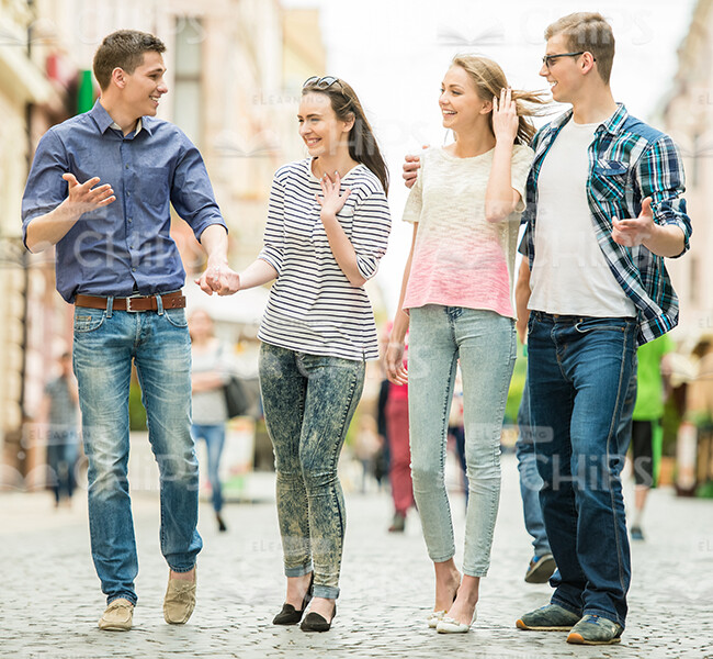 Four Friends Talking And Walking Through The Street Stock Photo