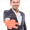 Happy Businessman Gives Puzzle Piece Stock Photo
