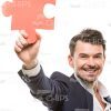 Smiling Man Throwing Puzzle Piece Up Stock Photo