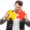 Stock Photo Of Businessman Tries To Connect Two Pieces Of Puzzle Stock Photo