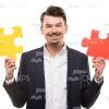 Cheerful Man Holding Puzzle Pieces Stock Photo