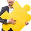 Happy Young Businessman With Large Yellow Puzzle Piece Stock Photo